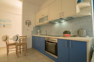 a kitchen with blue cabinets and a stove top oven at Sunset Home Crete in Paránimfoi