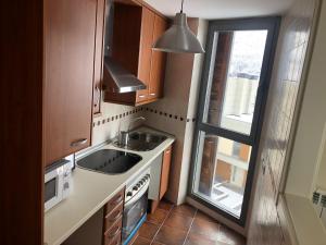 una pequeña cocina con fregadero y ventana en Apartamentos Las Margas Golf Formigal Ordesa, en Sabiñánigo
