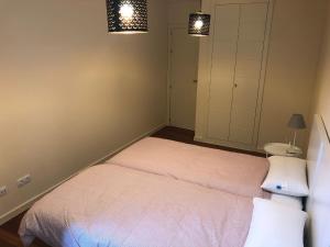 1 dormitorio con 2 camas y 2 luces en Apartamentos Las Margas Golf Formigal Ordesa, en Sabiñánigo