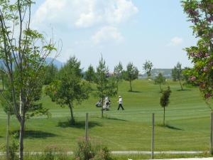 dos personas caminando en un campo de golf en Apartamentos Las Margas Golf Formigal Ordesa, en Sabiñánigo