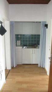 eine Küche mit weißen Schränken und blauen Vorhängen in der Unterkunft Appartement am See in Podersdorf am See