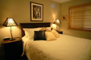 a bedroom with a large white bed with two lamps at Apartment 407, Contemporary Decor in Canmore