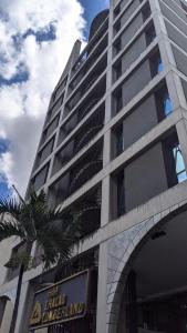 a tall building with a palm tree in front of it at Hotel Chacao Cumberland in Caracas