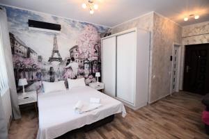 um quarto com uma cama branca e um mural da Torre Eiffel em Ioana Studio Mamaia Nord em Mamaia Nord – Năvodari