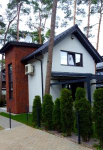 a white and red house with a tree at Comfort Villa in Pobierowo