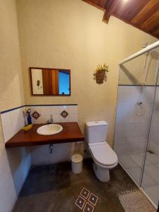 a bathroom with a toilet and a sink and a shower at Pousada Aconchego do Caboclo in Monteiro Lobato