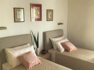two beds in a bedroom with pink and white pillows at Aliki Studios in Boukari