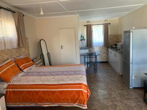 a bedroom with a bed and a kitchen with a refrigerator at Furnished self-catering bedsitter in Lusaka