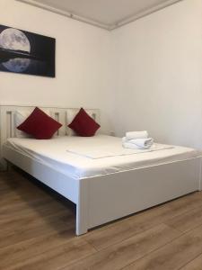a white bed with red pillows in a room at Beside Airport in Otopeni