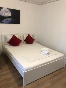 a white bed with two red pillows on it at Beside Airport in Otopeni