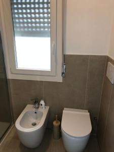łazienka z umywalką, toaletą i oknem w obiekcie Marine House w Lignano Sabbiadoro