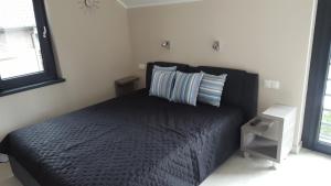 a bedroom with a black bed with two pillows at Comfort Villa in Pobierowo
