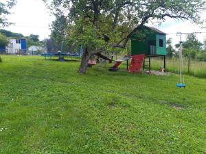 un parque con un árbol y un parque infantil en Cabana Ema, en Beclean