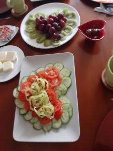 a plate with tomatoes and cucumbers and grapes on a table at Villa de Likua in Ružomberok