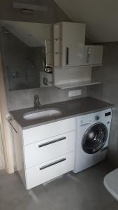 a bathroom with a sink and a washing machine at Comfort Villa in Pobierowo