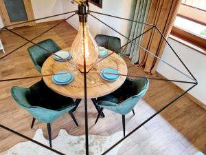 a dining room table with green chairs and a chandelier at Apartamenty widokowe "u Homera" in Zakopane