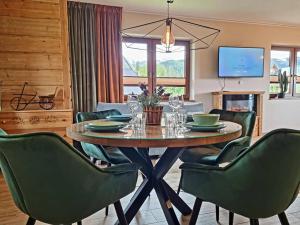 a dining room with a table and green chairs at Apartamenty widokowe "u Homera" in Zakopane