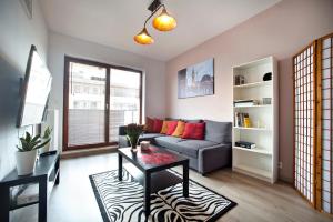 a living room with a couch and a table at Airport Okecie Klobucka P&O Serviced Apartments in Warsaw