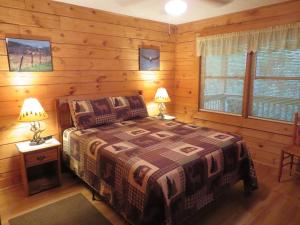 um quarto com uma cama num chalé de madeira em Misty Creek Log Cabins em Maggie Valley