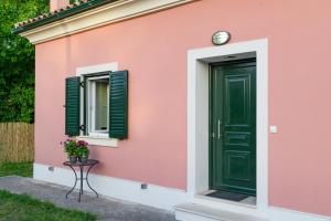Sunshine House Corfu في Anemómylos: منزل وردي مع باب أخضر ونافذة