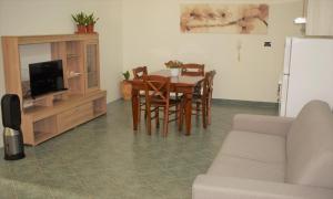 sala de estar con mesa, sillas y TV en Minerva casa vacanze, en Castro di Lecce