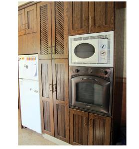 cocina con armarios de madera, microondas y nevera en Alojamiento rural " Las Carmenes ", en Algar