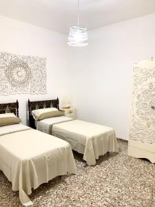 2 letti in una camera con pareti bianche di 4 Colonne Holiday Apartment a Nardò