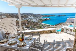 a table on a balcony with a view of the ocean at Villa Thelgo Mykonos in Psarou