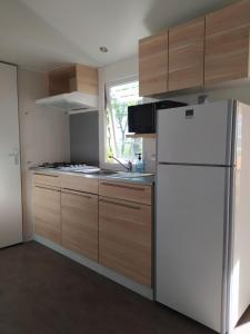 a kitchen with a white refrigerator and a window at Camping Les Peupliers in Saint-Père-en-Retz