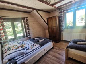 a bedroom with a bed and two windows at DoMarka całoroczny dom w Bieszczadach in Wetlina