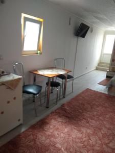 Zimmer mit einem Tisch, Stühlen und einem Fenster in der Unterkunft Olimpia Apartments in Alba Iulia