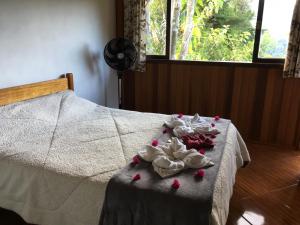 uma cama com algumas rosas sobre ela com uma mesa em Casa Sossego da Montanha em Visconde de Mauá