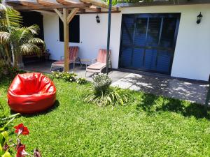 a yard with a red bean bag chair and a house at Encanto do Sol in Ponta do Sol
