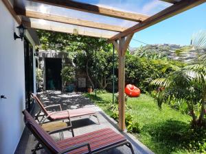 a patio with two chairs and a table and a pergola at Encanto do Sol in Ponta do Sol