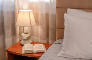 een nachtkastje met een lamp en een open boek bij Casa Voula in Corfu-stad