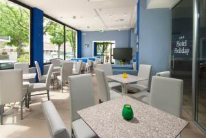 uma sala de jantar com mesas e cadeiras e uma televisão em Hotel Holiday em Misano Adriatico