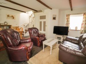 a living room with leather furniture and a flat screen tv at Mousehole Cottage in Carlisle