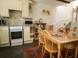 een keuken met een tafel en stoelen en een fornuis bij Mousehole Cottage in Carlisle