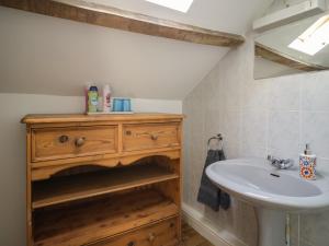 a bathroom with a sink and a wooden cabinet at Mousehole Cottage in Carlisle +3 photos