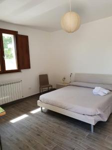 a bedroom with a bed and a chair and a window at Sonnellino in Maremma in Massa Marittima