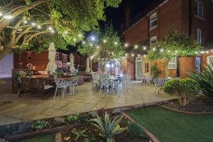 a patio with tables and chairs at night with lights at Somerset House Boutique Hotel and Restaurant in Portsmouth
