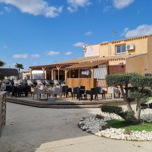 a group of chairs and tables in front of a building at Les sable du midi 3 in Valras-Plage