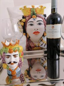 a bottle of wine next to two statues of masks at I TRE CUORI in Taormina