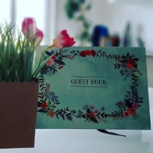 un libro de invitados sentado sobre una mesa con flores en B&B La Gatta Bianca, en Oliveri