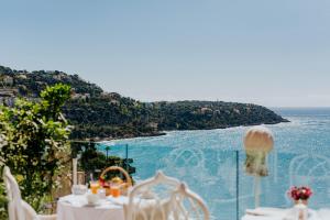 una mesa con sillas blancas y vistas al océano en Hôtel Le Roquebrune, en Roquebrune-Cap-Martin