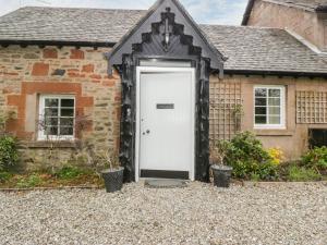 an old stone house with a white door at Ellanderroch in Glasgow