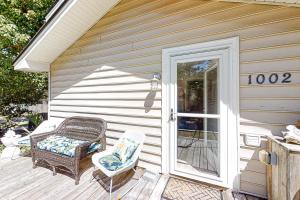 a porch with a wicker chair and a door at Beach Bum Bungalow in Folly Beach