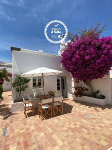 a patio with a table and a tree with purple flowers at Azul Sul in Tavira