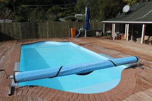 a blue swimming pool on a wooden deck at Parsloe's Cottage in Coromandel Town