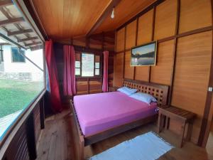 a bedroom with a purple bed in a wooden room at Chale com agua de nascente e com vista panoramica in Lumiar